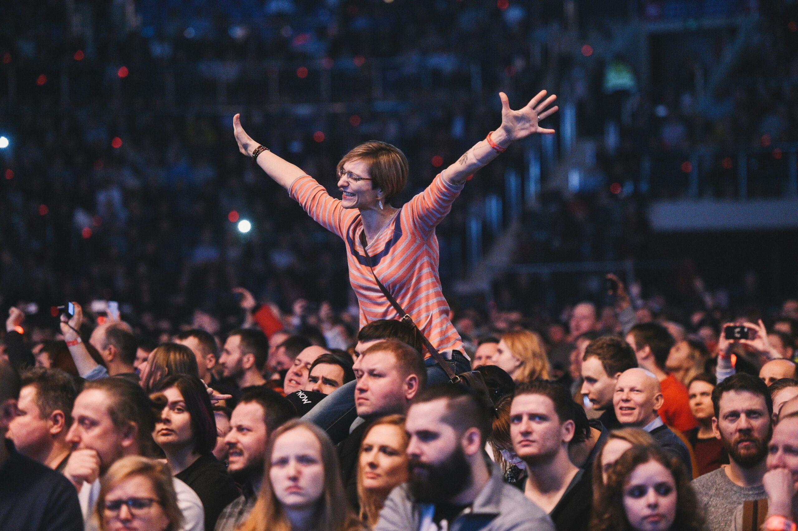 A woman joyfully cheers amidst a lively concert crowd, exuding energy.